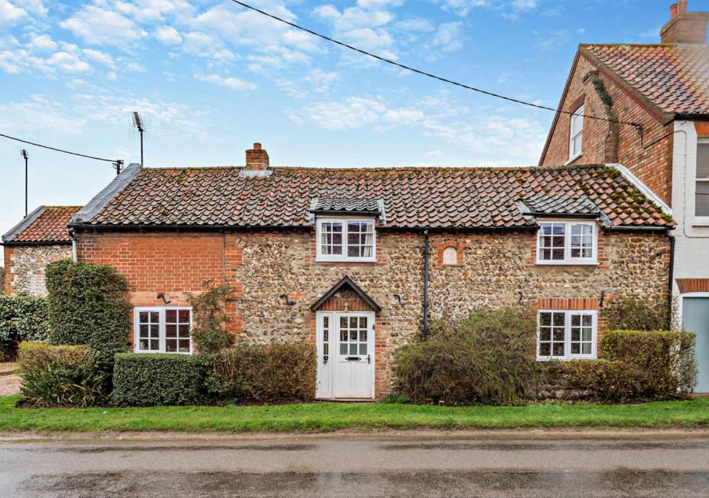 an old brick house with a white door at Barmstone Cottage in Brancaster