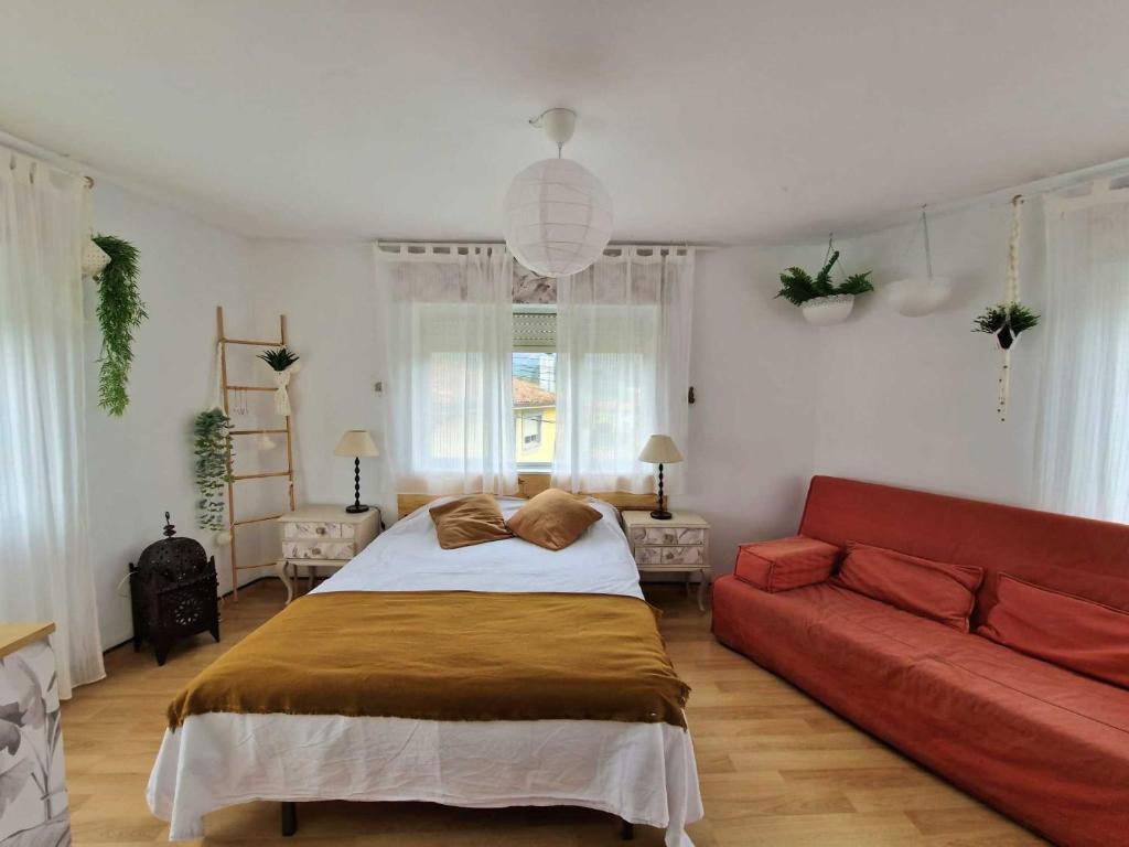1 dormitorio con 1 cama y 1 sofá rojo en Vivienda Vacacional Villa Cobijero, en La Pereda de Llanes