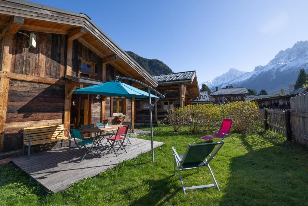 a deck with chairs and a table with an umbrella at Chalet le petit bornand in Les Houches