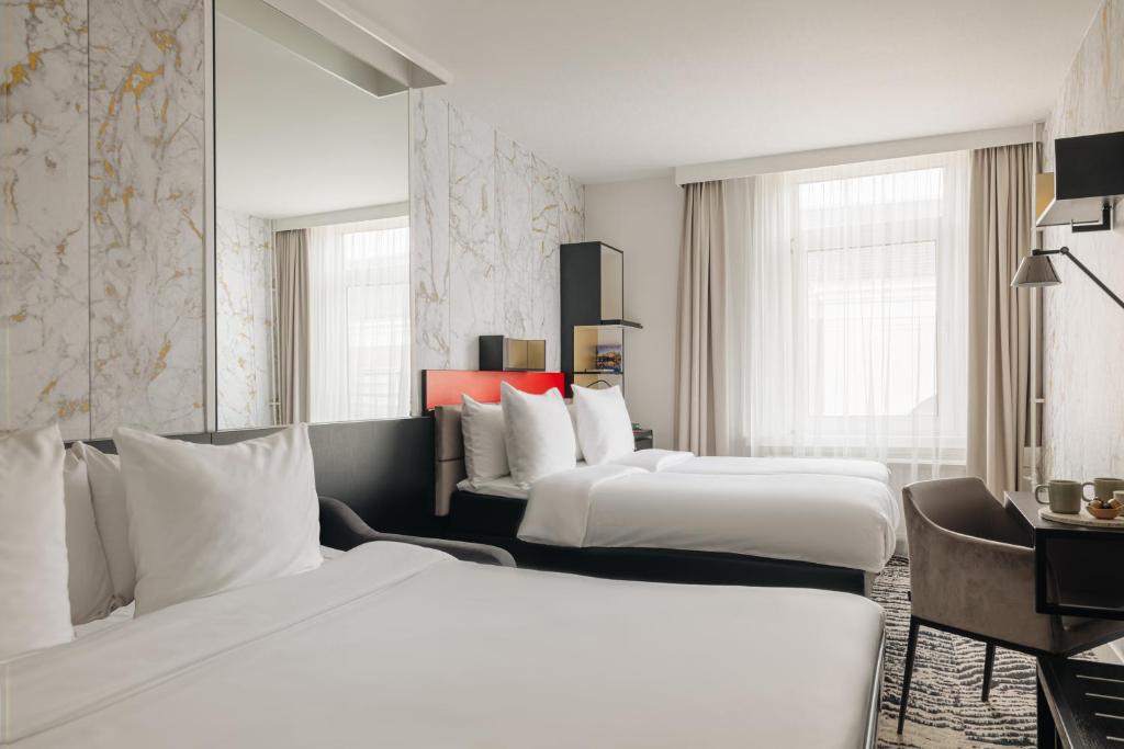 a hotel room with two beds and a desk at The Lancaster Hotel Amsterdam in Amsterdam