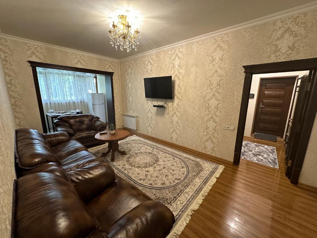 a living room with a leather couch and a television at Your cozy apartment "Centro Parkside" in the City center in Samarkand