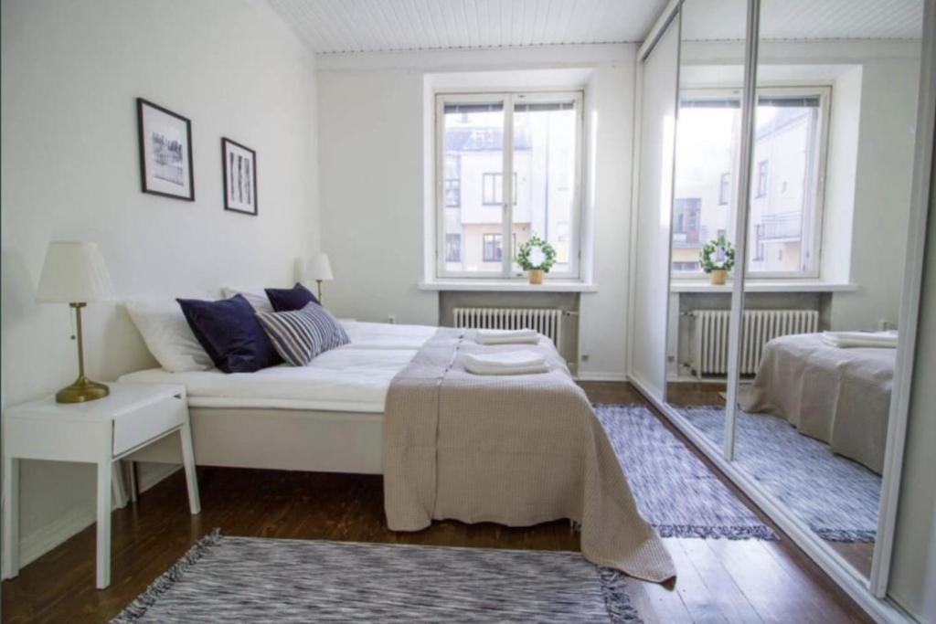 um quarto branco com uma cama e um espelho em 2ndhomes Fabianinkatu Apartments em Helsinque