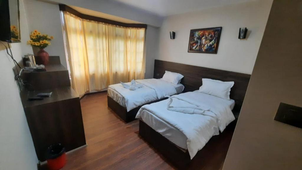 um quarto de hotel com duas camas e uma janela em Hotel Olive Branch Darjeeling Near Mall Road - Excellent Customer Service - Parking Facilities - Best Seller em Darjeeling