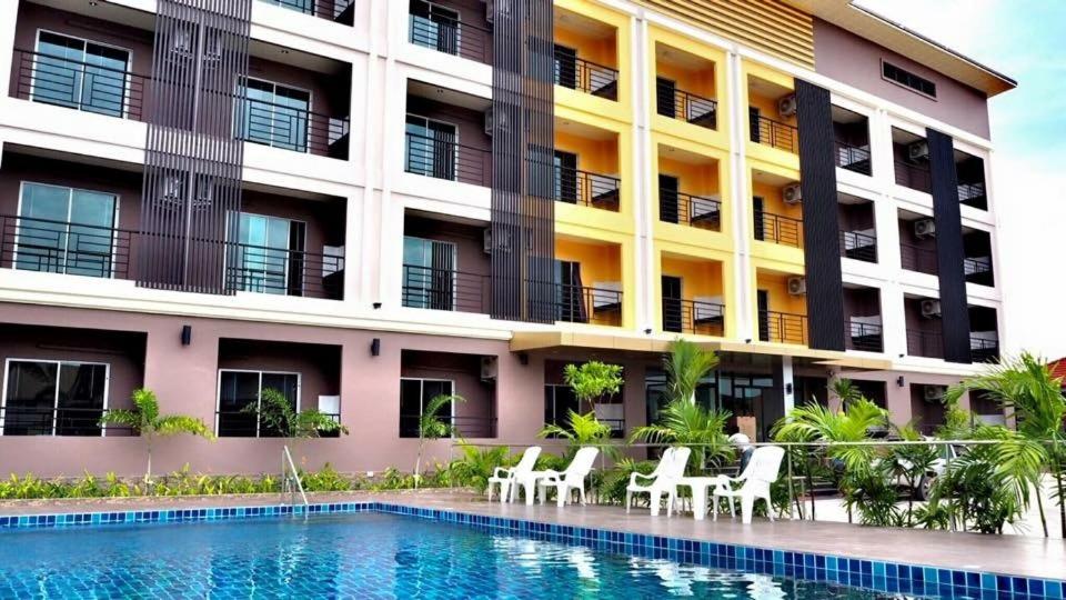 a hotel with a swimming pool in front of a building at B Space Residence in Nong Prue