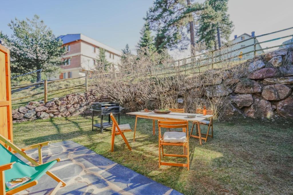 una mesa y sillas en un patio con una pared de piedra en La Molina IX, en La Molina