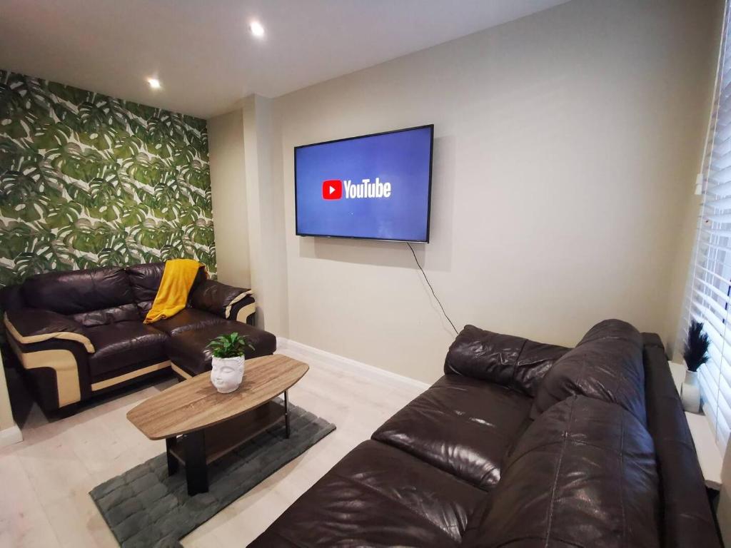 ein Wohnzimmer mit einem Sofa und einem TV an der Wand in der Unterkunft 4br Modern Botanic House in Belfast