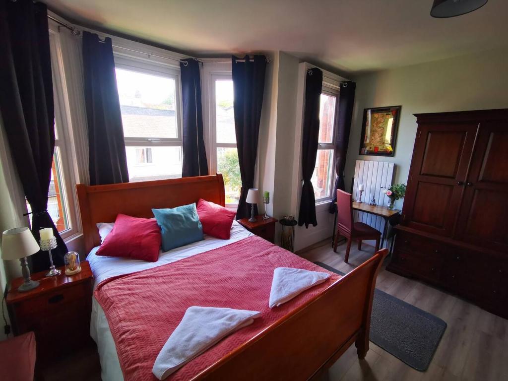 a bedroom with a bed with red sheets and colorful pillows at 4 Bed Boutique House Lisburn Road in Belfast