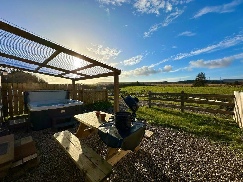 un patio con vasca idromassaggio, tavolo e recinzione di Forest View Cottage - Private Hot Tub a Ballynameen