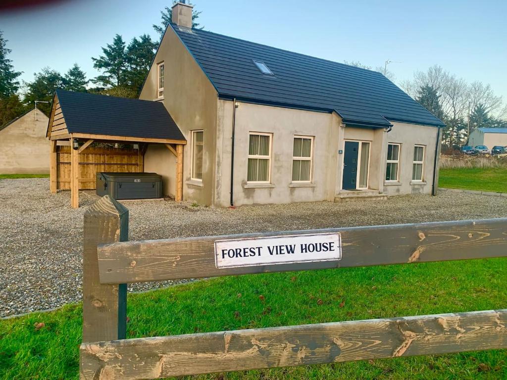 una casa con un cartel en una valla en Forest View House & Hot Tub Sleeps 9, en Ballynameen