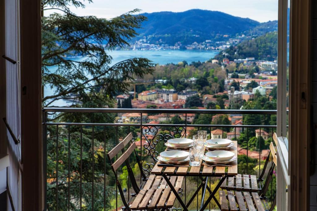 a table with plates and glasses on a balcony with a view at Vista Lario Apartment - Aqua Apartments in Cernobbio