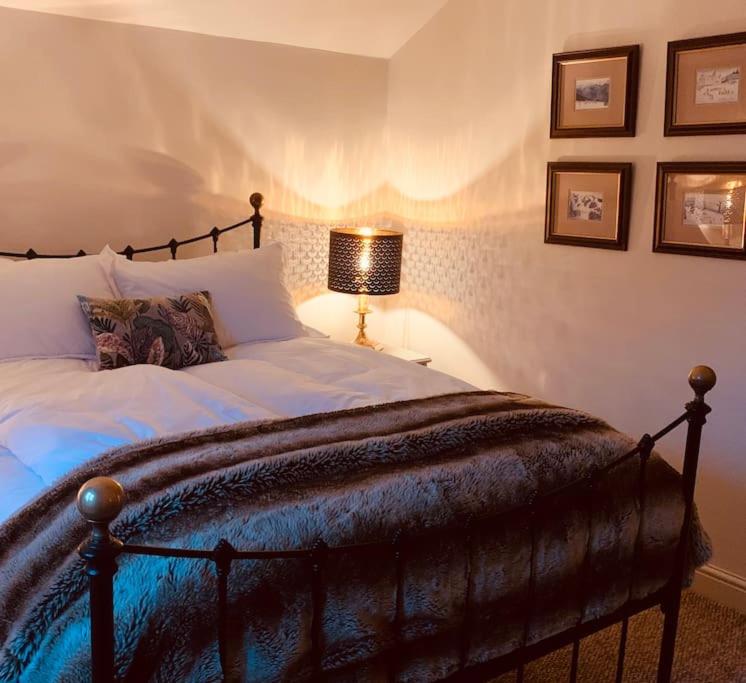 a bedroom with a large bed and a lamp at Exmoor, Devon - charming cottage , characterful and brimming with Hygge! in Tiverton