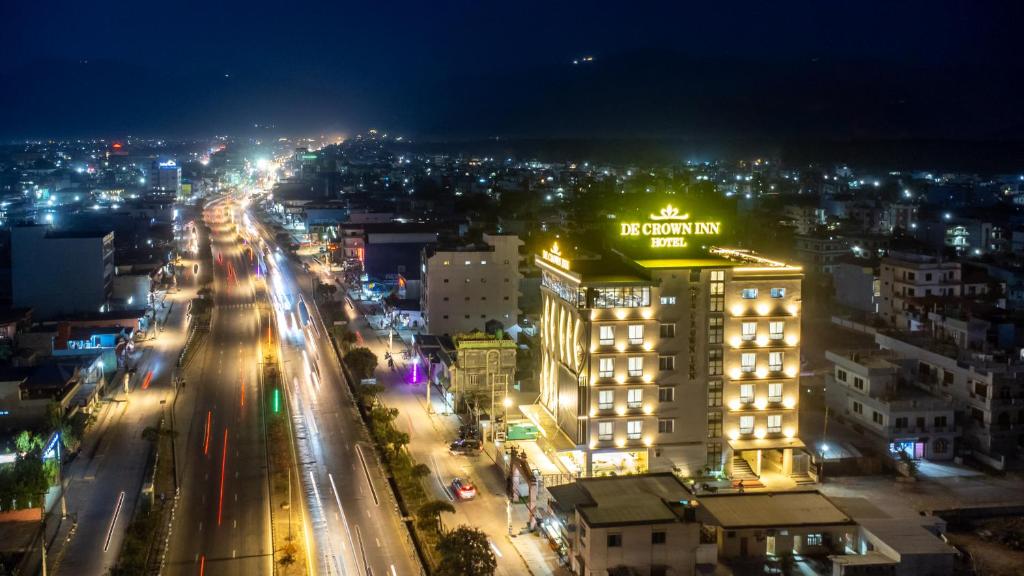 een stad verlicht in de nacht met een gebouw bij De Crown Inn in Jogīkuti