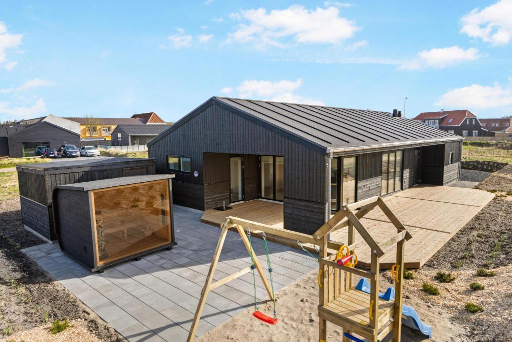 a black house with a playground in front of it at Newly Built Luxury Holiday Home, Sensommervej 4 in Løkken
