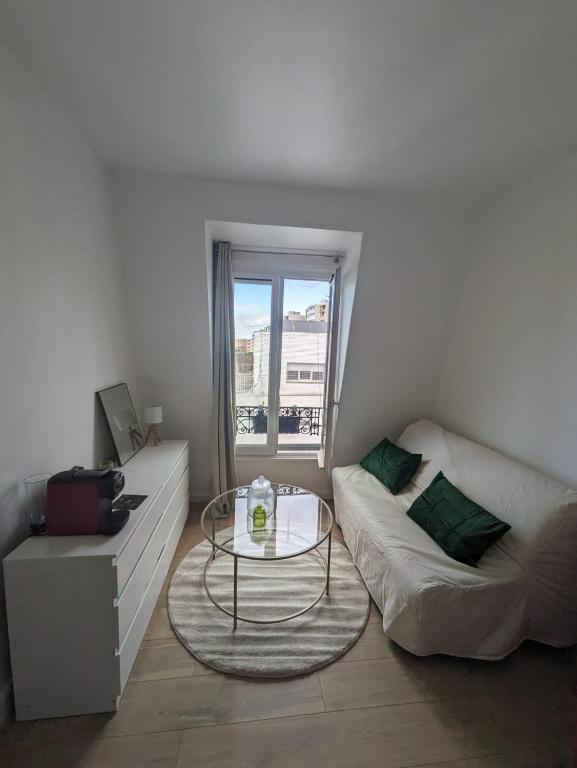 un salon avec un canapé et une table en verre dans l'établissement Studio Cosy Proche Métro, à Paris