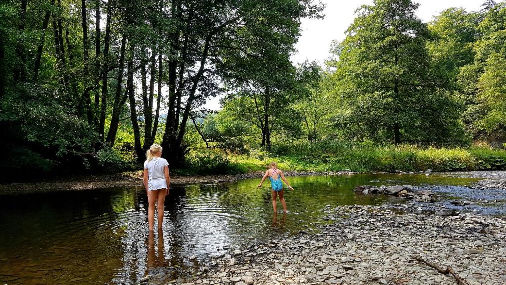 two women walking in the water in a river at Camping Vallee de l'Our in Untereisenbach