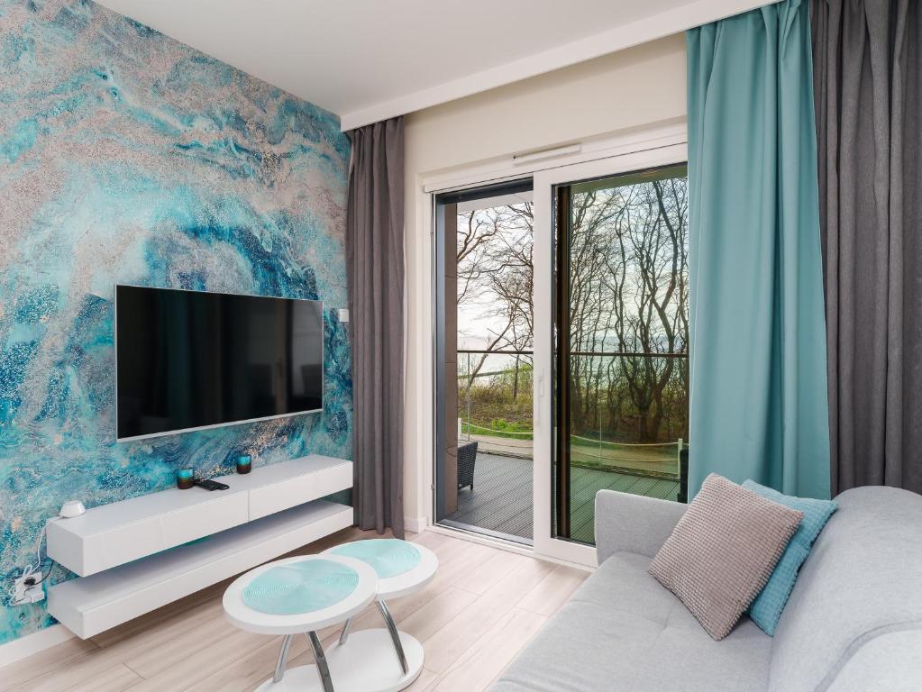 a living room with a tv on a wall at Apartament z Widokiem na Morze - Błękitna Perła by Perłowa Przystań Rent in Sianozety