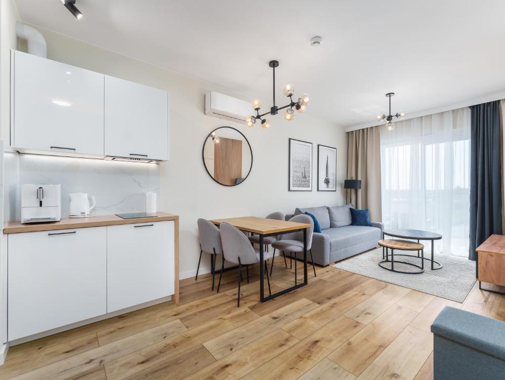 a kitchen and living room with a table and a couch at Apartament Przy Plaży z darmowymi rowerami - by Perłowa Przystań Rent in Sianozety