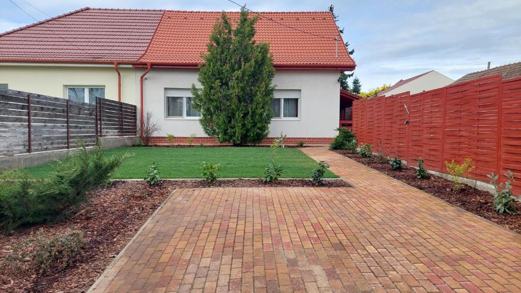 a house with a brick walkway in front of a yard at Dunakeszi Nap Apartman in Dunakeszi