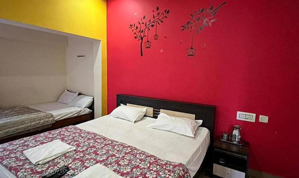 sypialnia z 2 łóżkami i czerwoną ścianą w obiekcie FabExpress Guru Residency w mieście Kodaikānāl