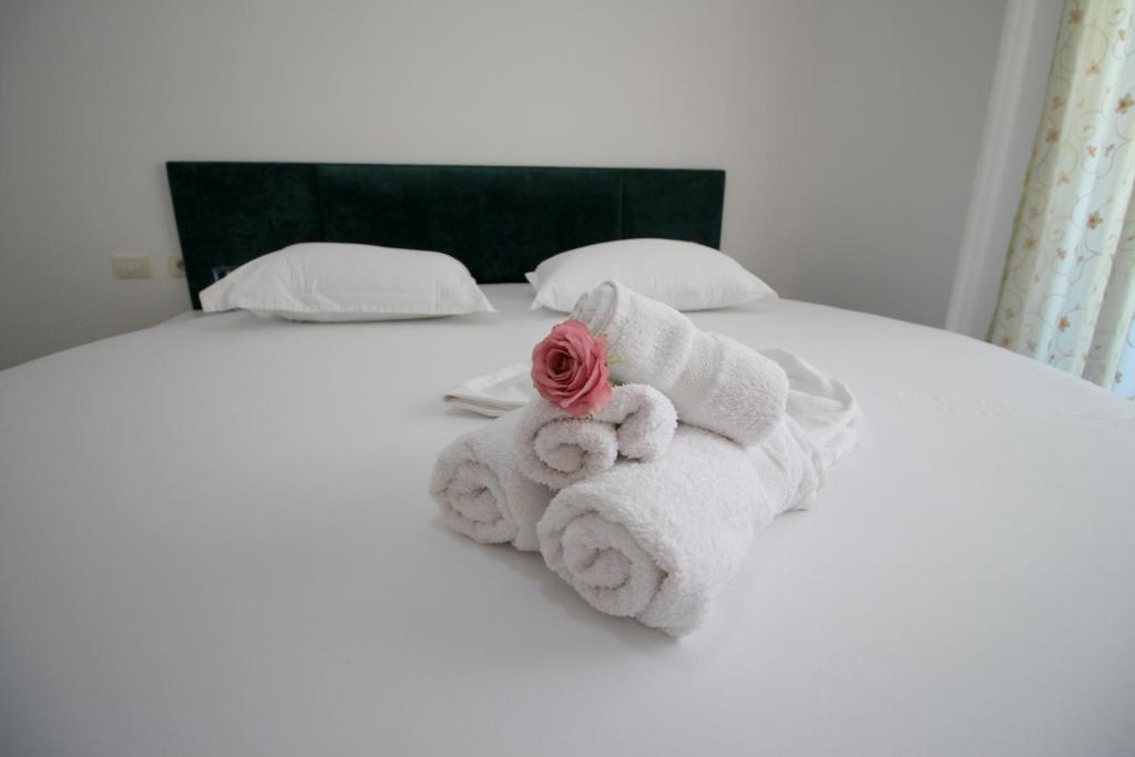 einen Haufen Handtücher auf einem Bett mit einer Rose in der Unterkunft July Seaview Apartments in Sarandë