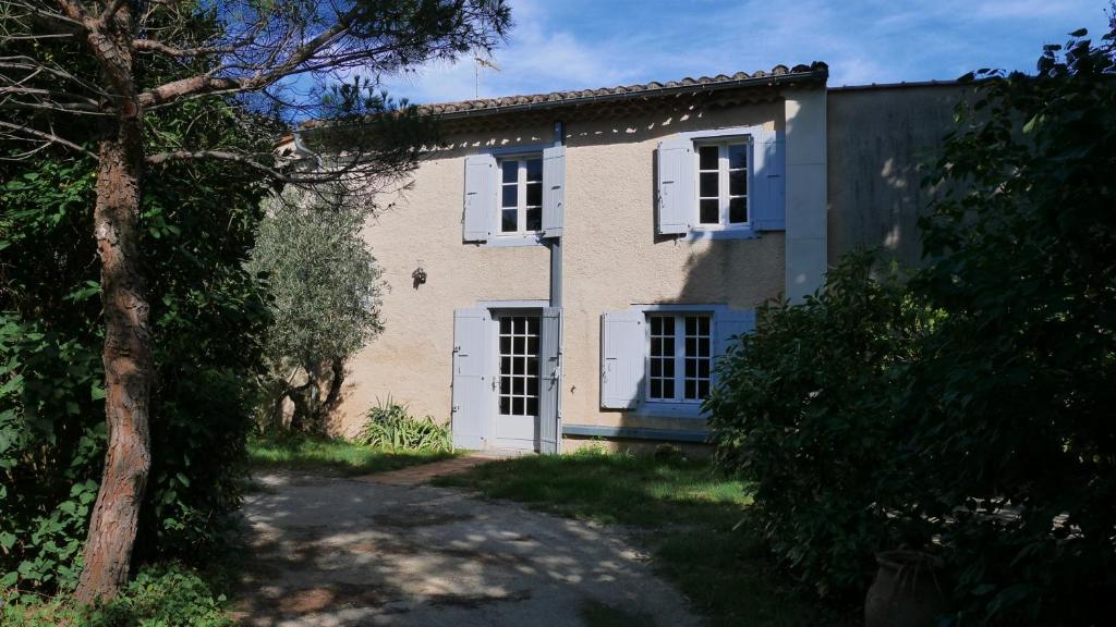 une vieille maison avec des fenêtres blanches et un arbre dans l'établissement La Maison d'En Face, à Saint-Affrique-les-Montagnes