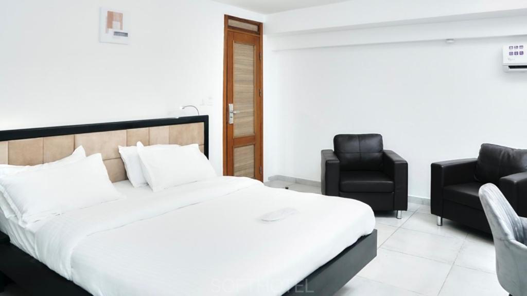 - une chambre avec un lit et une chaise noire dans l'établissement SOFT HOTEL, à Douala