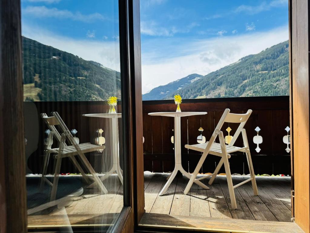 a balcony with two chairs and a table with a view at Chalet Franzi - Ruhiges Chalet mit Bergblick, Garten und gratis Eintritt ins Solarbad in Dorfgastein