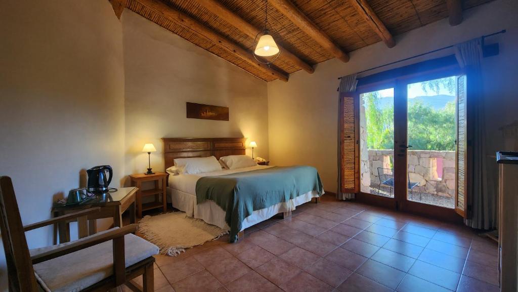 a bedroom with a bed and a large window at Las Terrazas Hotel Boutique in Tilcara