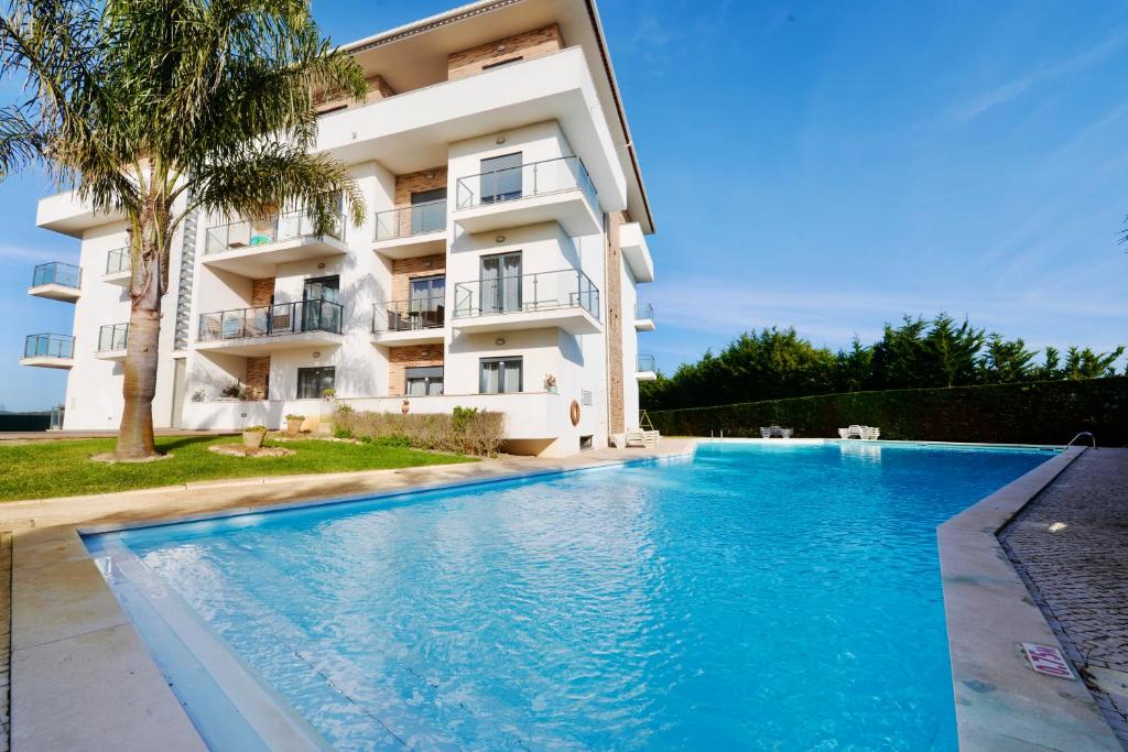 a hotel with a swimming pool in front of a building at Vela - Apartment in complex near the beach in São Martinho do Porto