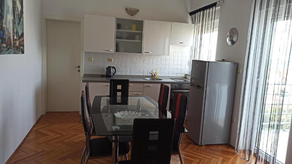 a kitchen with a glass table and a refrigerator at Apartment SKY in Novalja
