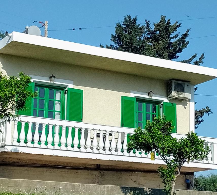 a house with green shutters and a balcony at Viktor's house by the sea in Boukari