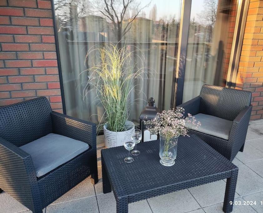 two chairs and a table with flowers on a patio at Apartament Nad Strugą, klimatyzacja, parking,taras in Toruń