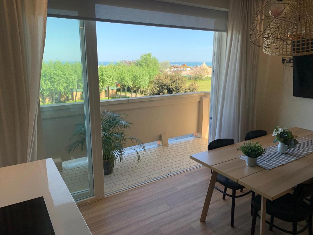 Una sala de estar con una mesa y una gran ventana. en Appartamento Fronte Mare Sottomarina, en Sottomarina