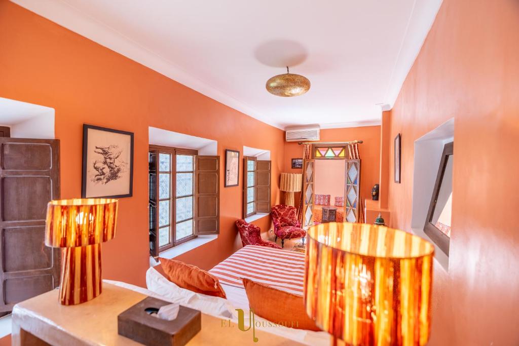 a living room with orange walls and two lamps at Riad El Youssoufi in Marrakesh