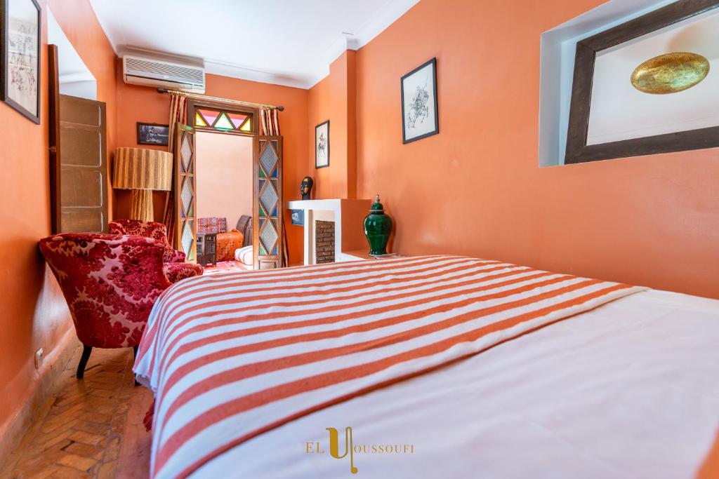 a orange bedroom with a bed and a chair at Riad El Youssoufi in Marrakesh
