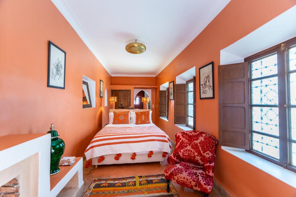 a bedroom with orange walls and a bed and a chair at Riad El Youssoufi in Marrakesh