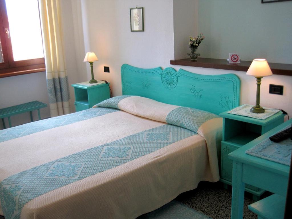 sypialnia z niebieskim łóżkiem z dwoma stołami w obiekcie Hotel Moderno w mieście Santa Teresa Gallura