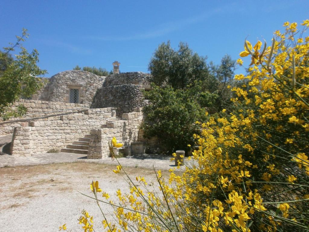 オストゥーニにあるTrullo Villa Giuliana con giardino Posizione panoramica Free wifiの階段と黄色い花の古い石造りの建物