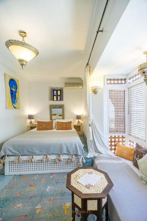 a bedroom with two beds and a table at Riad El Youssoufi in Marrakesh