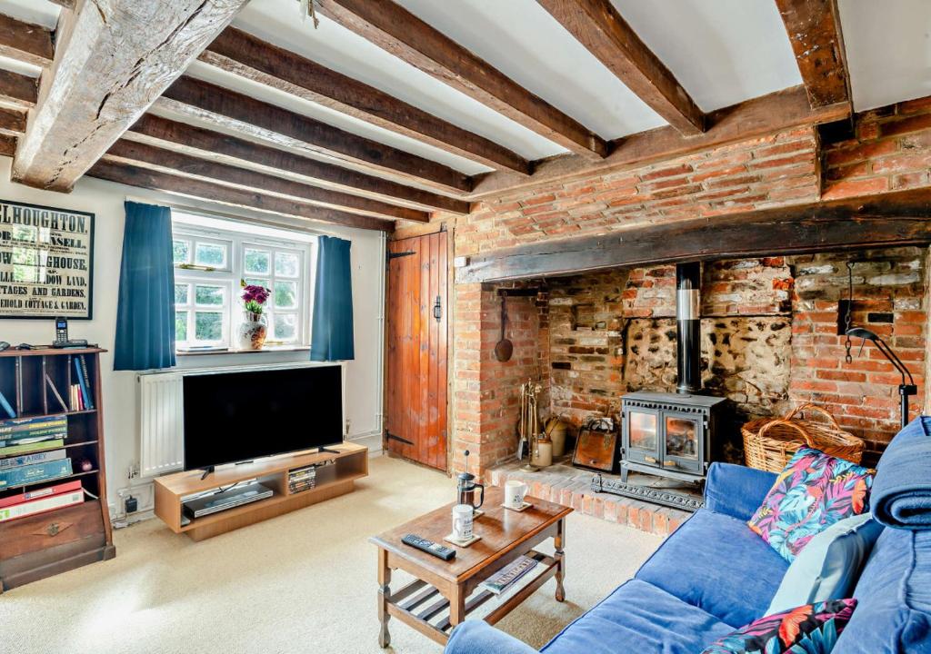 a living room with a blue couch and a brick wall at Badgers Hideaway in Helhoughton