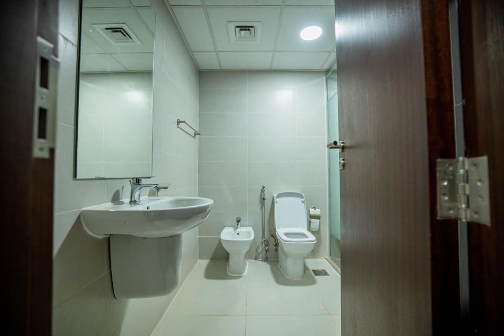 ein Badezimmer mit einem Waschbecken, einem WC und einem Spiegel in der Unterkunft Niamey Mall & Residence in Niamey