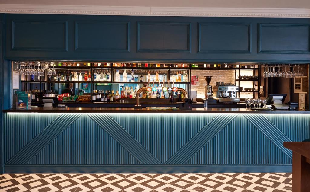 a bar in a restaurant with a blue wall at Thistle London Heathrow Terminal 5 in Hillingdon