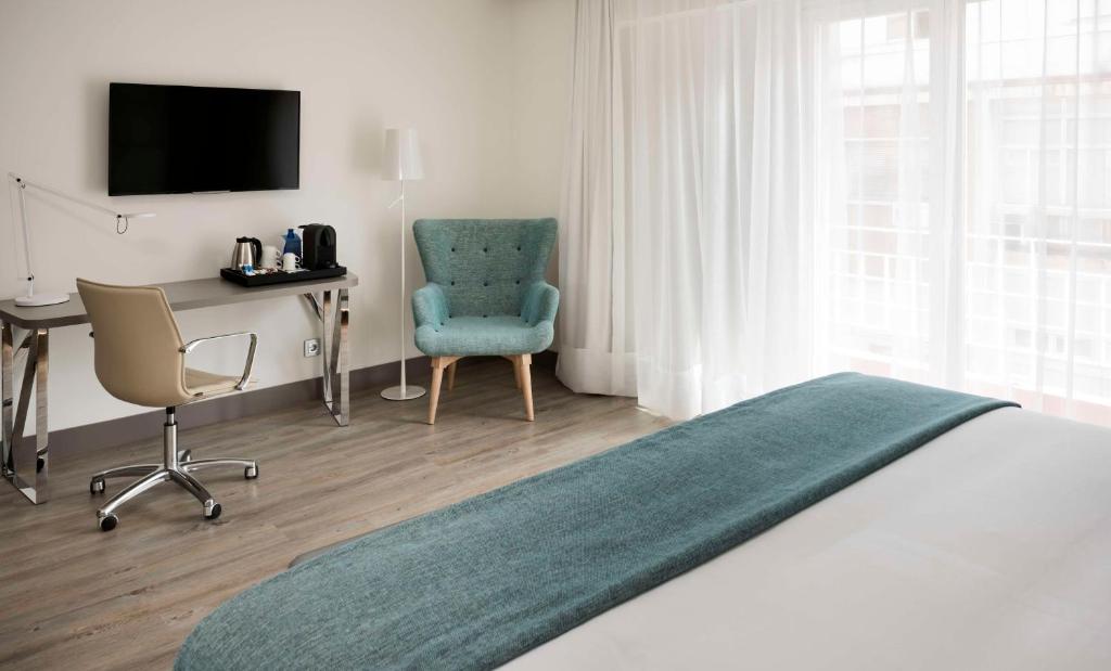 um quarto com uma cama, uma secretária e uma cadeira em NH Madrid Zurbano em Madri