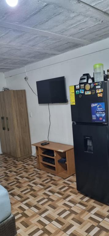 a room with a refrigerator and a table and a tv at Apartatamento pequeño amueblado in San Salvador