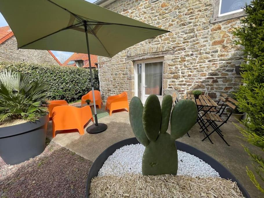 a cactus and an umbrella in front of a building at Gîte le 7 de Coeur, Baie Mont St Michel in Dragey