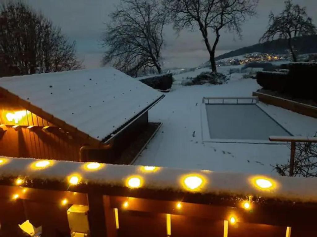 a snow covered backyard with a tennis court and lights at Chalet avec vue panoramique sur les Montagnes du Mole et la chaîne des Aravis piscine chauffée à 5 min des pistes de la station des Brasses in Viuz-en-Sallaz