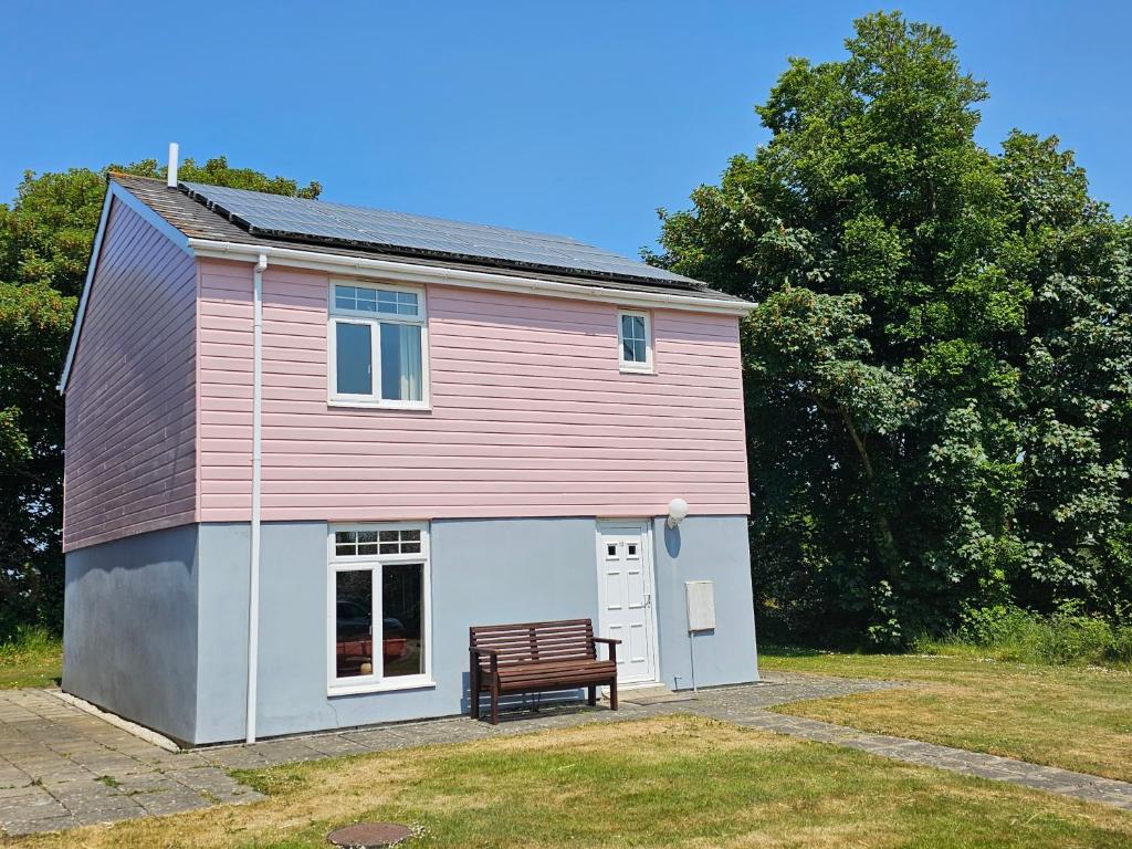a pink house with a bench in front of it at Atlantic Reach Gold Lodge 12 in Newquay
