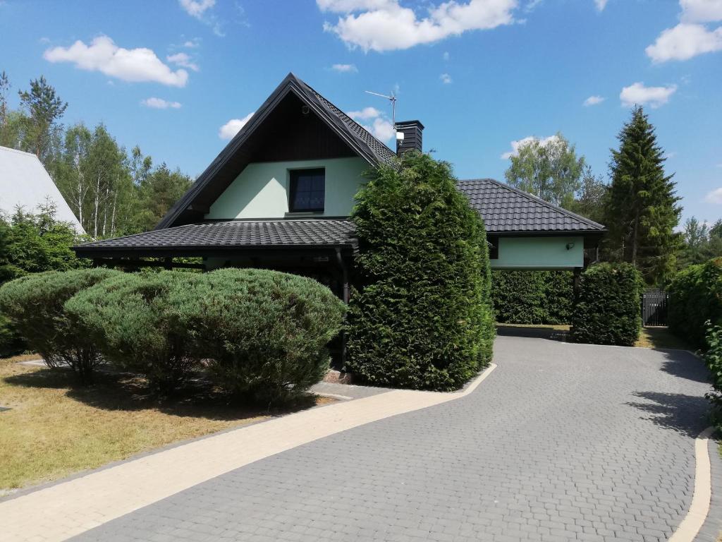 a house with a black roof and bushes at Domki Letniskowe Jerutki in Świętajno