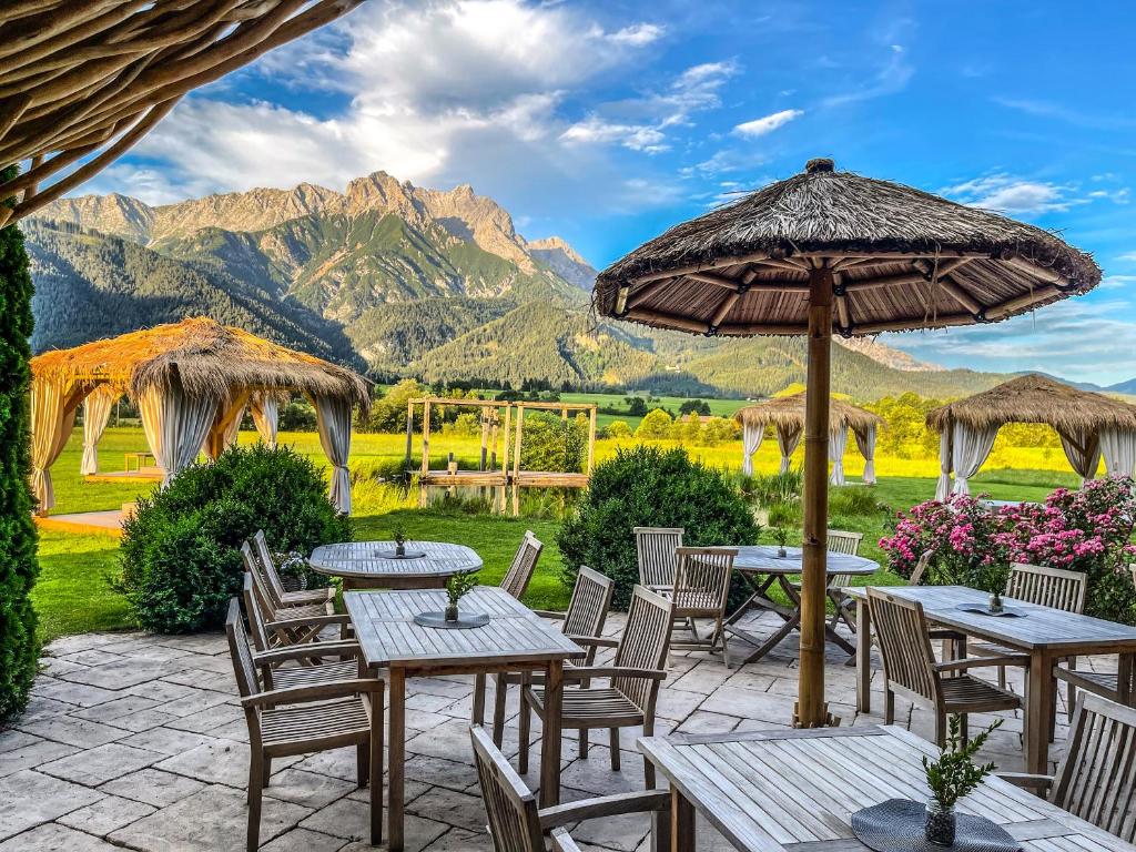 un patio con mesas y sillas con montañas en el fondo en Hotel Saliter Hof en Saalfelden am Steinernen Meer