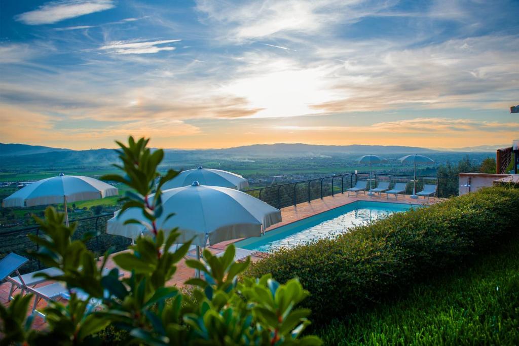 ein Pool mit Sonnenschirmen auf einem Hügel in der Unterkunft Le Terrazze di Cancellara in Foligno